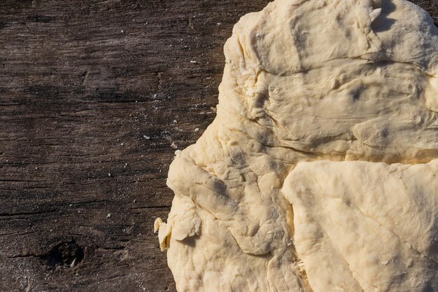 Rauw vers gistdeeg voor het bakken op rustieke houten tafel. Bovenaanzicht