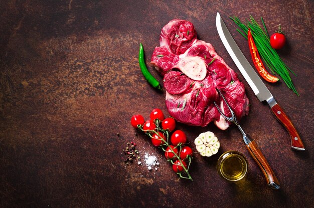 Rauw vers vlees steak met kerstomaatjes hete peper knoflookolie en kruiden op donkere stenen betonnen achtergrond Banner