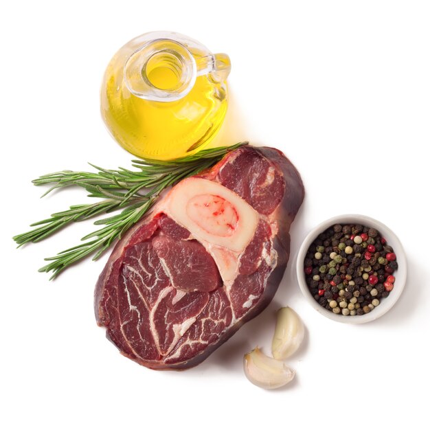 Rauw vlees biefstuk met bot, kruiden, rozemarijn en koken ingrediënten geïsoleerd op een witte achtergrond. bovenaanzicht.