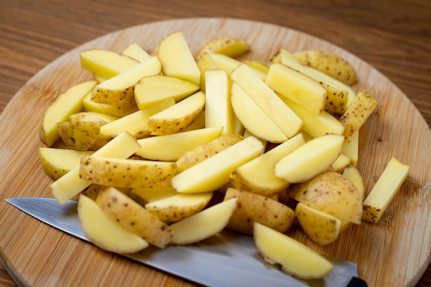 Rauwe aardappelen gesneden in frietjes op een houten plank
