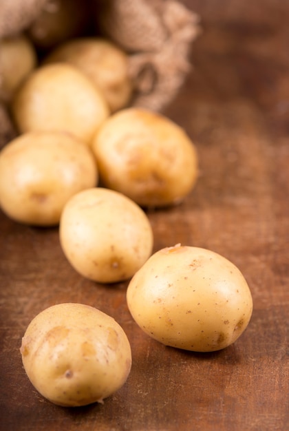 Rauwe aardappelen in de zak op de houten achtergrond