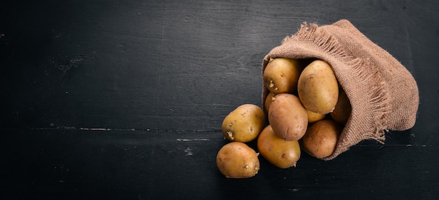 Rauwe aardappelen op een zwarte houten achtergrond Koken Vrije ruimte voor tekst Bovenaanzicht