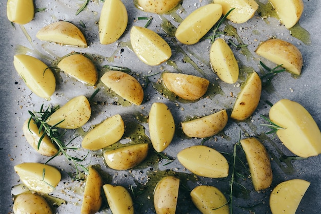 rauwe aardappelpartjes met olie en peper op bakplaat, voedselconcept achtergrond