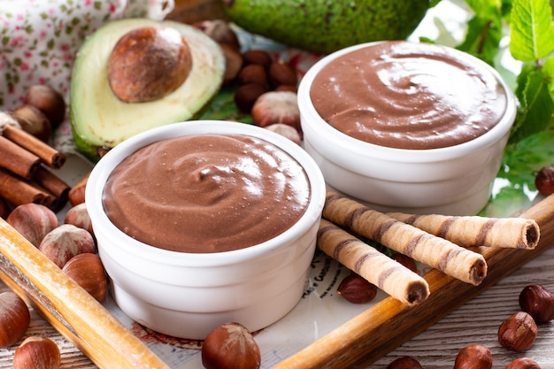 Rauwe avocado-chocolademousse gegarneerd met chocolade en munt, selectieve focus. Gezond veganistisch chocoladedessert.