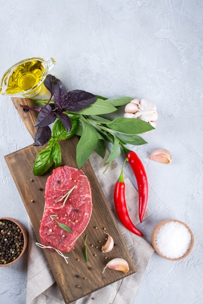 Rauwe biefstuk met ingrediënten voor het koken op de snijplank. Bovenaanzicht met kopie ruimte