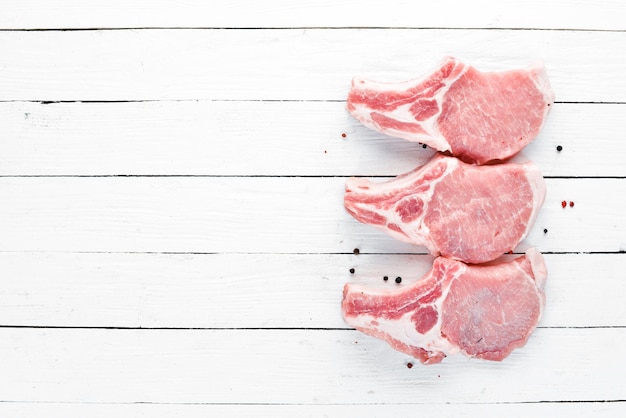 Rauwe biefstuk op het bot Vlees met specerijen en kruiden Op een witte houten achtergrond Bovenaanzicht Gratis kopieerruimte
