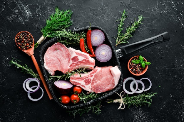 Rauwe biefstuk op het bot Vlees met specerijen en kruiden Op een zwarte stenen achtergrond Bovenaanzicht Gratis kopieerruimte
