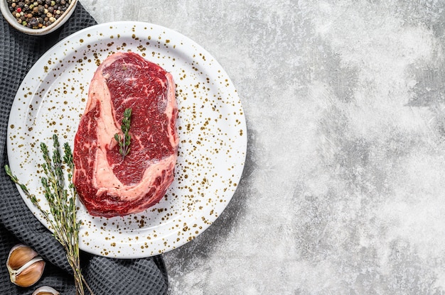 Rauwe biefstuk ribeye en kruiden op een grijze tafel