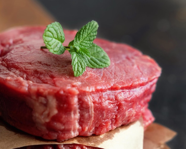 Rauwe biefstuk van de ossenhaas op een houten bord op donkere achtergrond close-up Geportioneerde filet mignons met kruiden en ingrediënten Concept van zomervoedsel