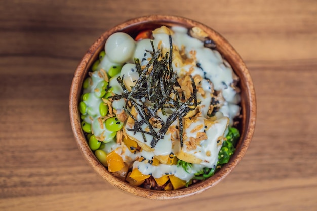 Rauwe biologische poke bowl met rijst en groenten close-up op het tafelblad van bovenaf horizontaal