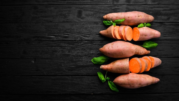 Rauwe biologische zoete aardappelen op een houten ondergrond dieetvoeding bovenaanzicht