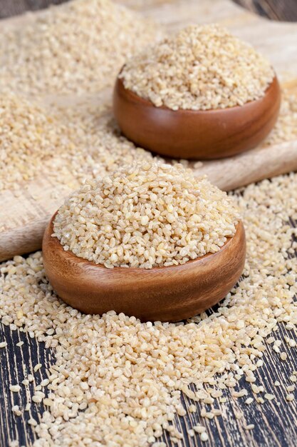 Rauwe bulgur pap die niet kookt, een grote hoeveelheid granen op een houten tafel, bulgur is gemaakt van tarwekorrel