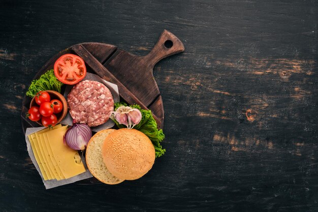 Rauwe burger Een hamburger met vlees koken Op een zwarte houten achtergrond Bovenaanzicht Gratis kopieerruimte