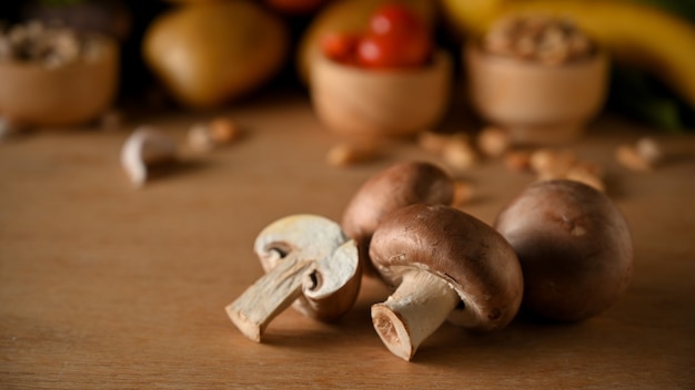 Rauwe champignonpaddestoelen en een dia van champignon op houten tafel. Gezond veganistisch ingrediënt.