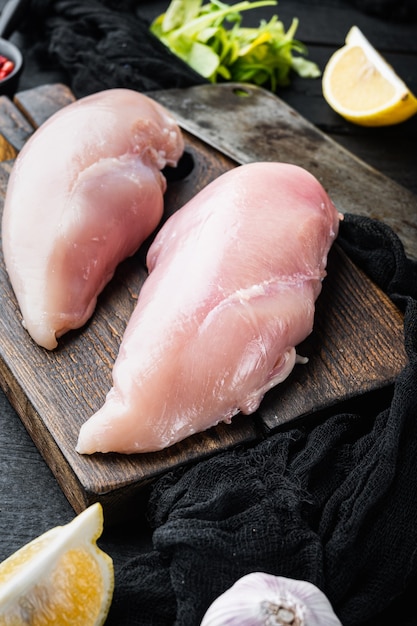 Rauwe crumbet kipfilet met ingrediënten met slagersmes op zwarte houten tafel