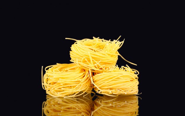 rauwe droge nest pasta met reflectie op zwart