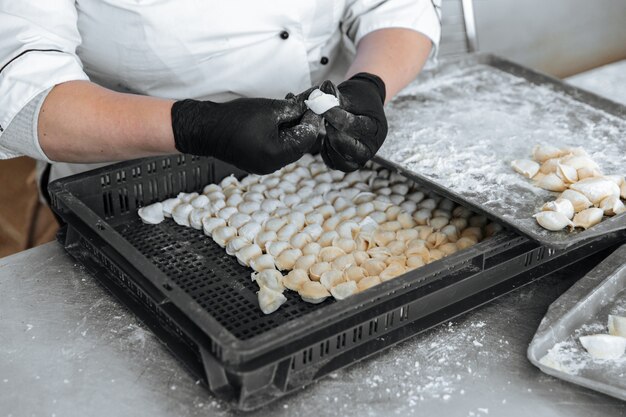 Rauwe dumplings het proces van het koken van een kok in handschoenen beeldhouwt ze