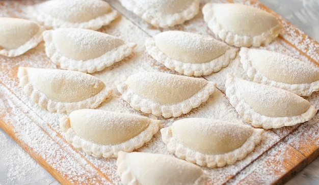 Rauwe dumplings op een houten bord op grijze tafel Het proces van het maken van dumplings Close up