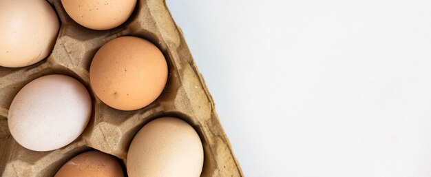 Rauwe eieren op een houten kom, op een witte achtergrond. verticale bovenaanzicht van bovenaf. geïsoleerd