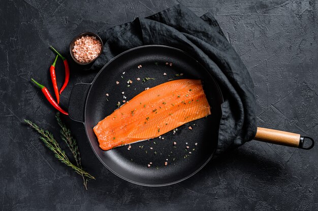 Foto rauwe forelfilet met zout en chilipeper in een pan. biologische vis. bovenaanzicht