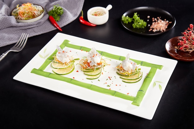 Rauwe garnalen, citroenschijfjes en groentesnippers op een bord met bamboepatroon