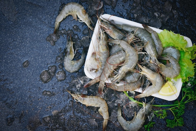 Rauwe garnalen op plaat plastic dienblad verse garnalengarnalen voor het koken met kruiden citroen groentesalade sla op donkere achtergrond in het visrestaurant