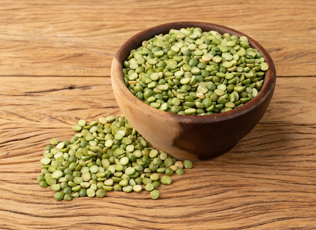 Rauwe gedroogde groene erwten in een kom over houten tafel.