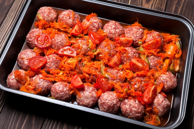 Rauwe gehaktballen met groenten op een bakplaat zijn klaar om te bakken in de oven selectieve focus
