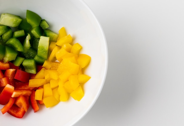 Rauwe gemengde rode, gele en groene paprika op een kom