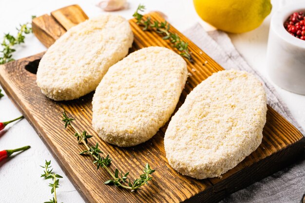 Rauwe gepaneerde patty schnitzels ingesteld op witte stenen tafel achtergrond