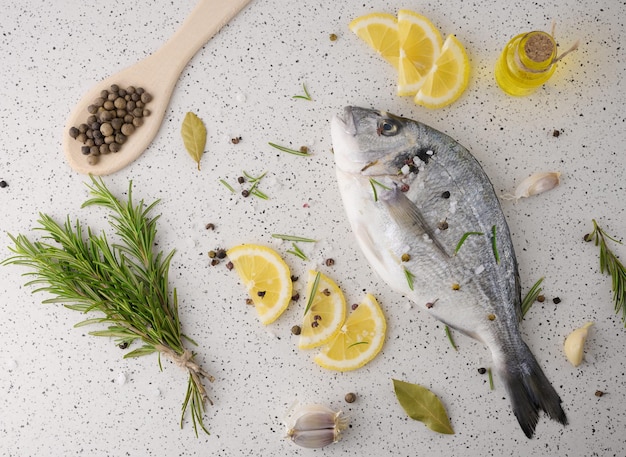 Rauwe hele dorado vis op wit bord en kruiden voor het koken bovenaanzicht op witte tafel