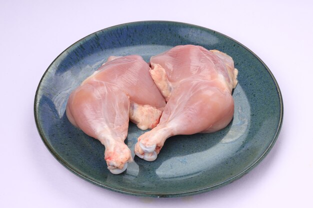 Rauwe hele kippenpoot zonder huid gerangschikt in een aqua rustieke blauwe plaat met witte achtergrond.
