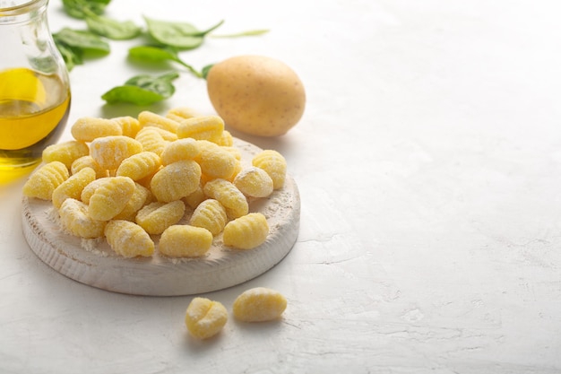 Rauwe Italiaanse gnocchi op een witte achtergrond met aardappel en spinazie met kopieerruimte