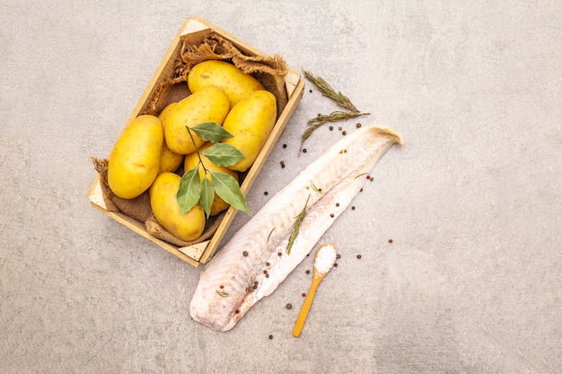 Rauwe jonge aardappelen en bevroren heekfilets met kruiden en specerijen