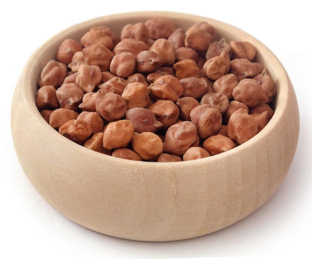 Rauwe kikkererwten in een houten kom op witte achtergrond