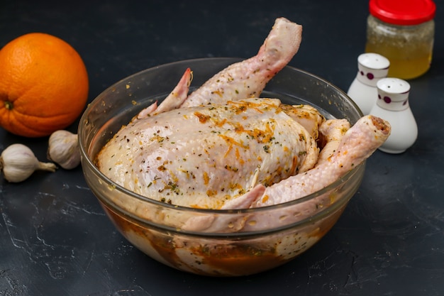 Rauwe kip in een kom in een sinaasappel-honingmarinade bereidt zich voor op bakken in de oven