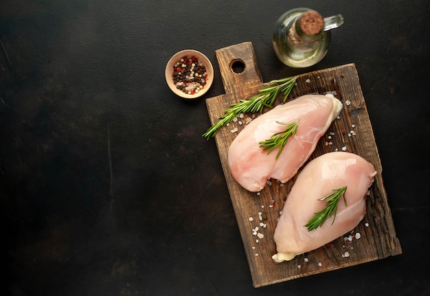 Rauwe kipfilet filets, klaar om te koken op een houten snijplank met kruiden. met kopie ruimte voor uw test