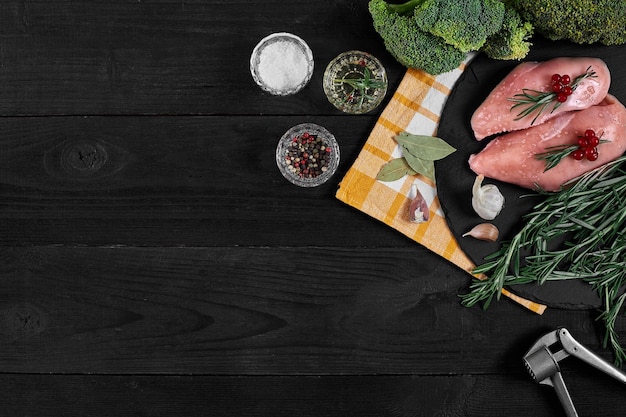 Foto rauwe kipfilet met kookingrediënten op zwarte leisteen tafel voedsel achtergrond bovenaanzicht kopieerruimte stilleven plat leggen