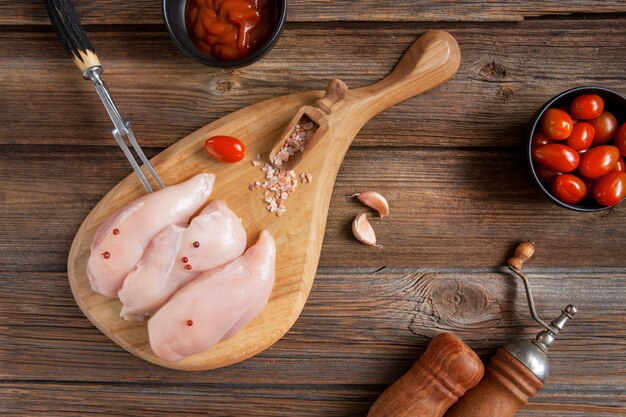 Rauwe kippenborstfilets met tomaten, ketchup en kruiden in rustieke stijl