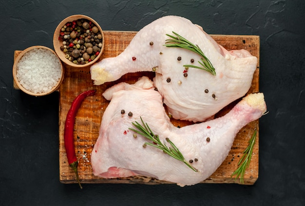 Rauwe kippenpoten met specerijen en kruiden klaar voor het koken op een stenen achtergrond.