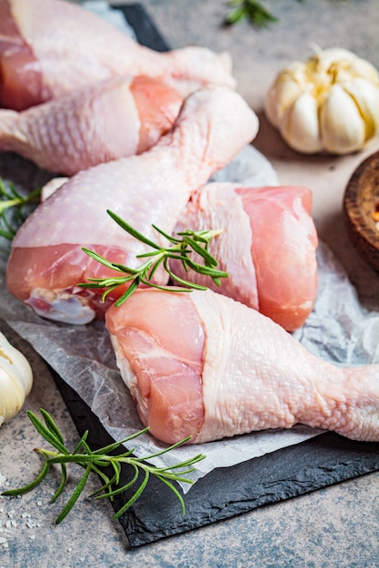 Rauwe kippenpoten op leisteen met kruiden, knoflook en rozemarijn. koken eten concept.