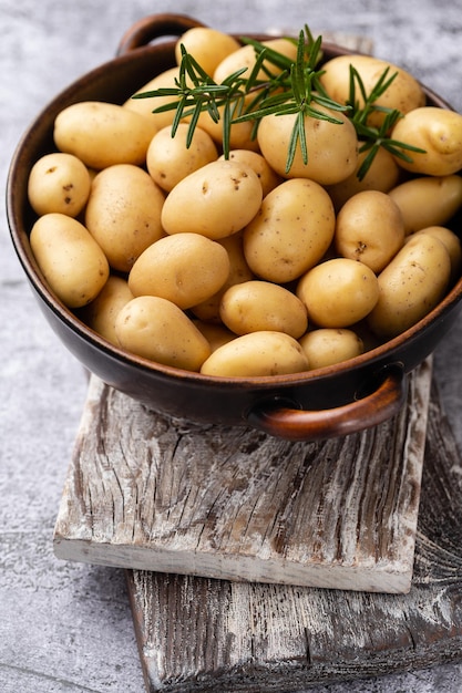 Rauwe kleine aardappelen in een gietijzeren koekepan op een achtergrond van beton.