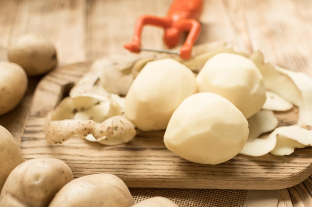 Rauwe knollen geschilde aardappelen op een houten ondergrond