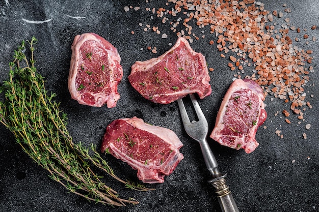 Rauwe lamslende steaks karbonades schnitzels op keukentafel Zwarte achtergrond Bovenaanzicht