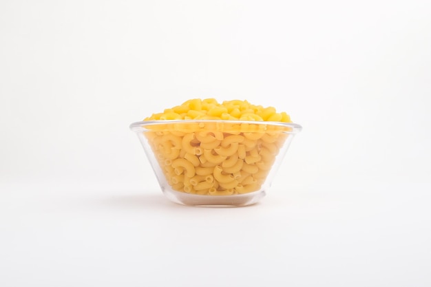 Foto rauwe macaroni-elleboogpasta op een zijaanzicht van een glazen kom