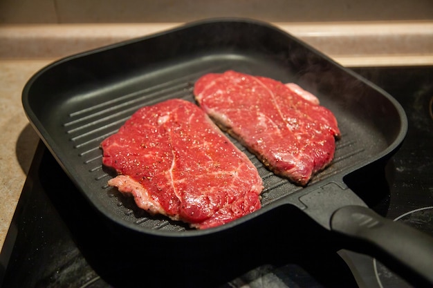 Rauwe minuut steak van gemarmerd rundvlees in een grillpan op een elektrisch kookoppervlak