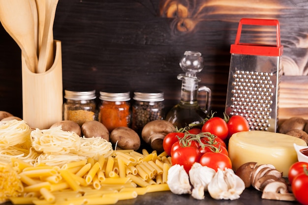 Rauwe ongekookte spaghetti, pasta en macaroni naast verse groenten op rustieke achtergrond
