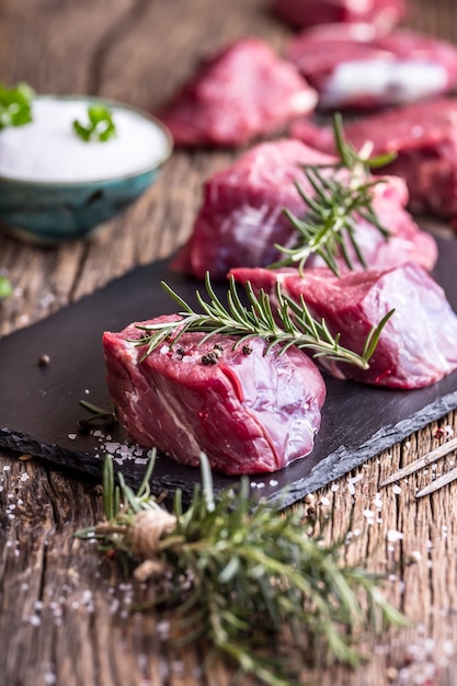 Rauwe ossenhaas steak op een snijplank met rozemarijn peper zout in andere posities