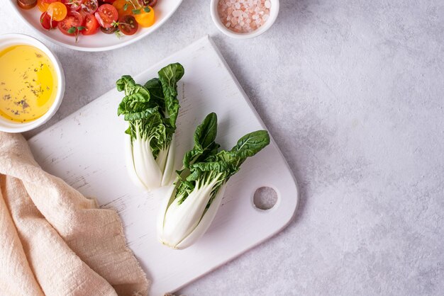 Rauwe paksoi kool op een snijplank op een witte plaat, verse groenten voor gezond eten.