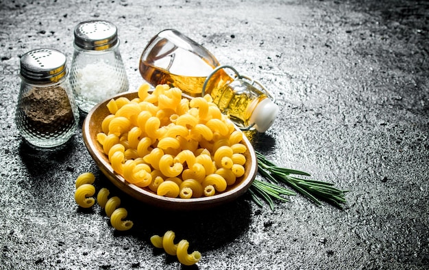 Rauwe pasta in kom met rozemarijnkruiden en olie in fles